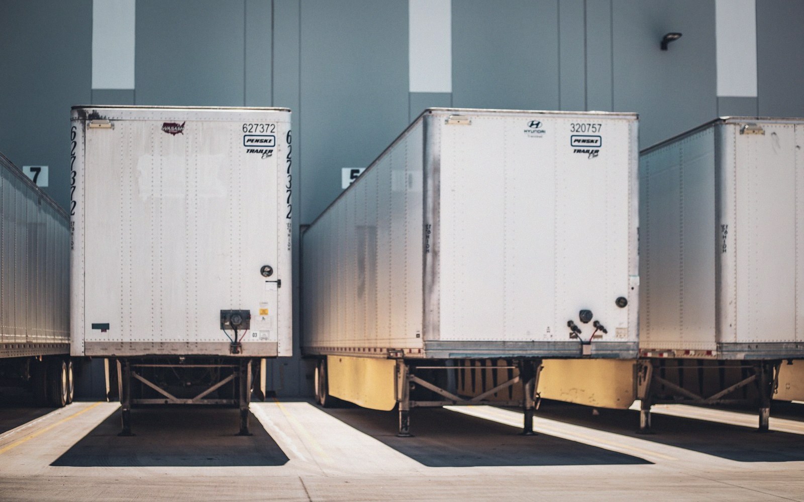 Rows of white trailers backed into loading dock bays at a warehouse