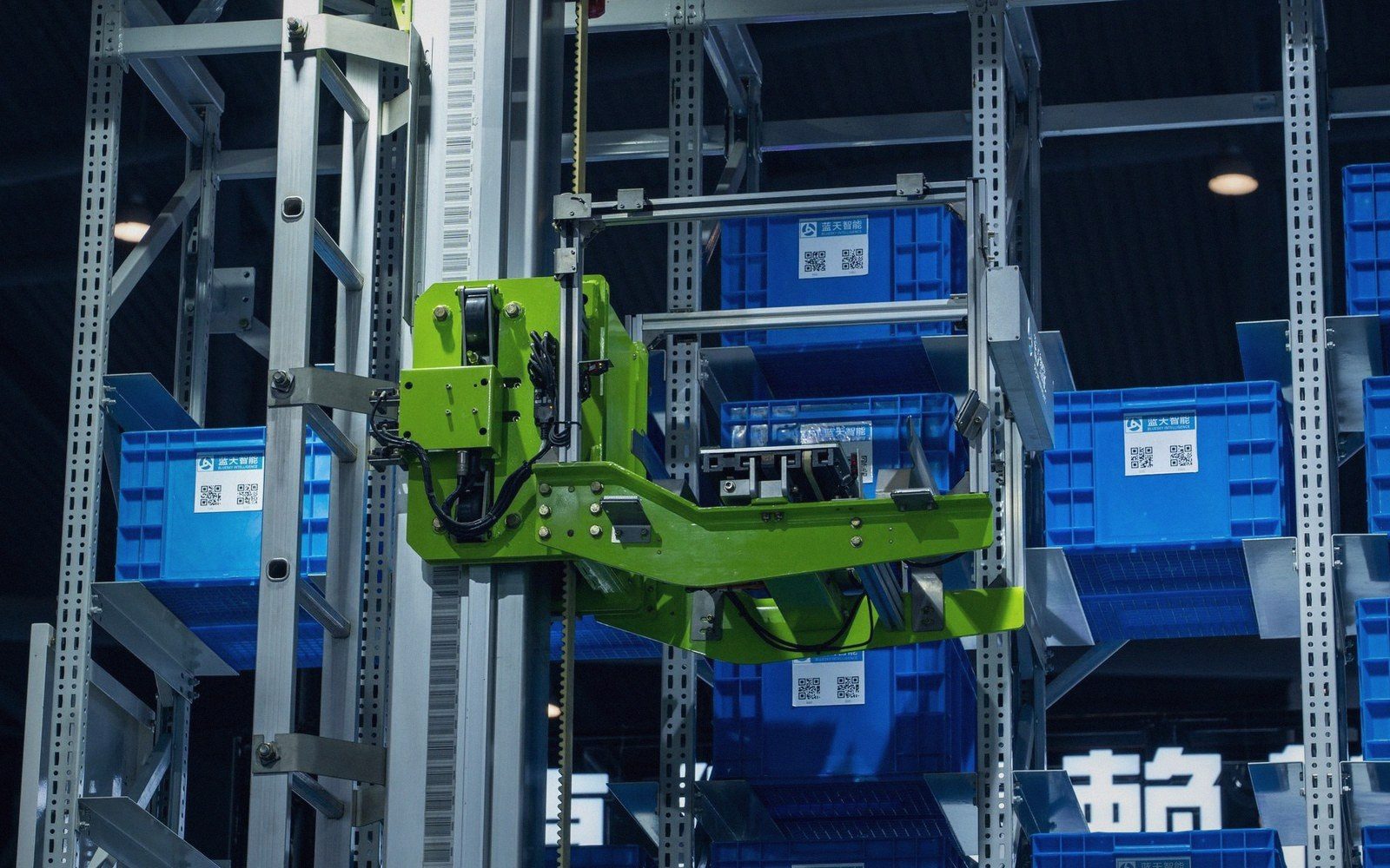 Automated robotic arm retrieves blue storage bins in a warehouse racking system